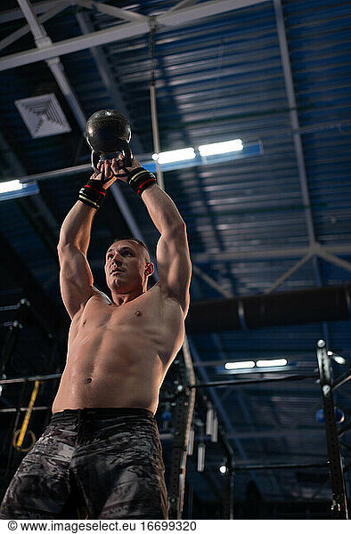Powerful bodybuilder lifting kettlebell in gym