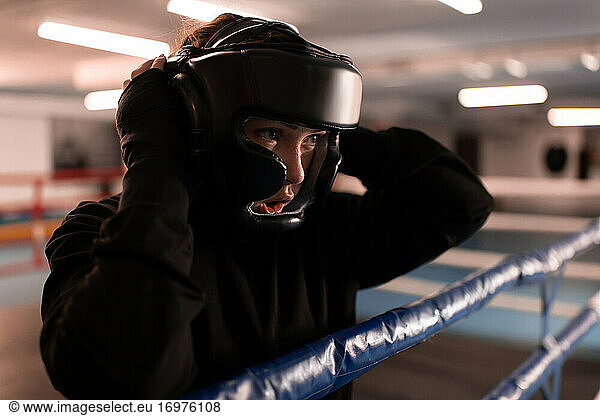 Powerful boxer adjusting safety helmet before fight