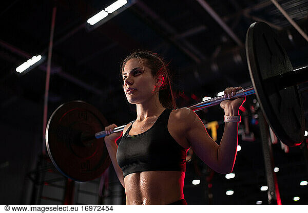 Powerful woman lifting barbell during functional training