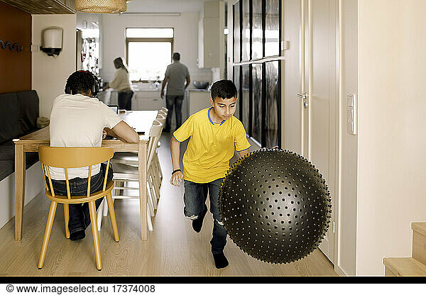 Pre-adolescent boy playing with fitness ball at home