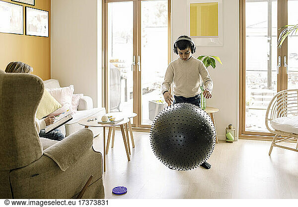 Pre-adolescent boy playing with fitness ball in living room