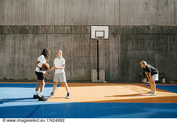 Pre-adolescent female basketball players playing at sports court