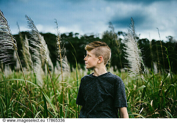 Pre teen boy in front of grass field and forest