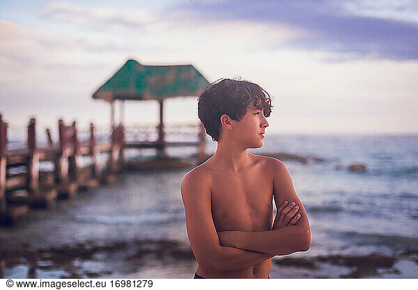 Pre teen boy looking away with a wooden pier in the background.