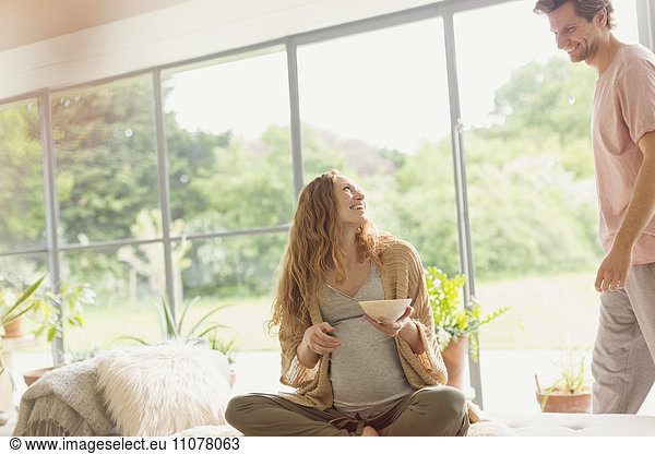 Pregnant couple eating in living room