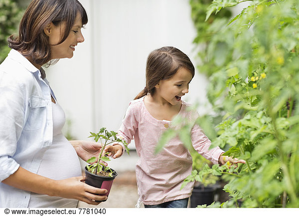 Pregnant mother and daughter gardening together