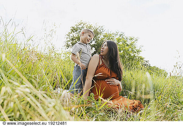 Pregnant mother looking at son in meadow