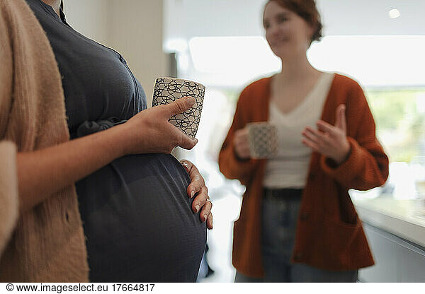 Pregnant woman and friend talking and drinking tea