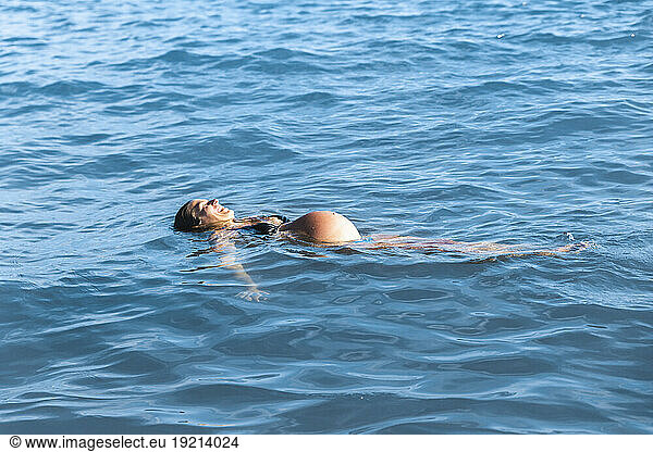 Pregnant woman floating on sea water