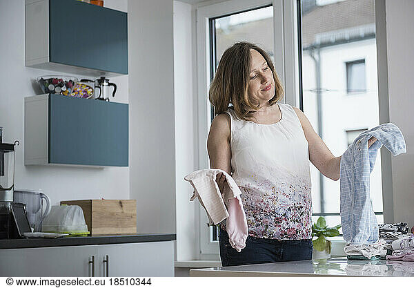 Pregnant woman folding baby clothes in the kitchen  Munich  Bavaria  Germany