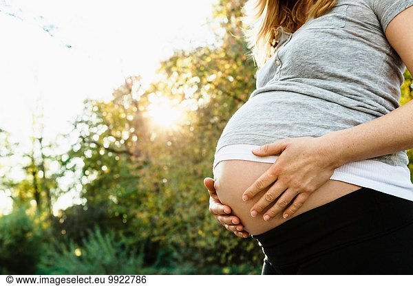 Pregnant woman holding belly  outdoors  mid section