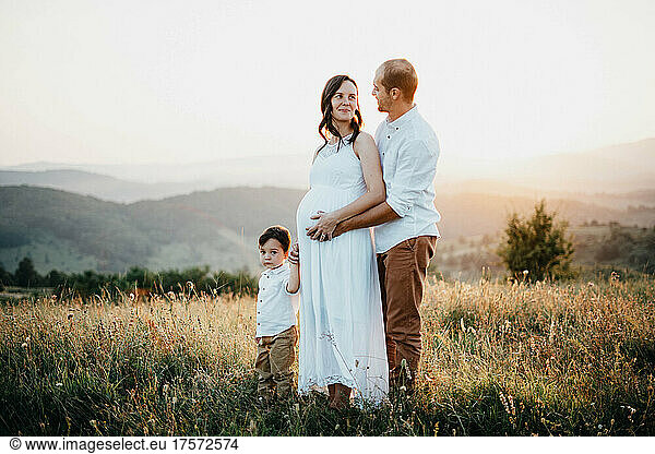Pregnant woman holding his son and husband hands at sunset