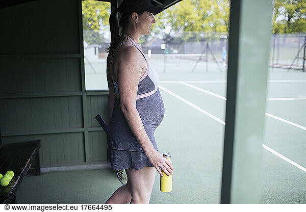 Pregnant woman in dress at tennis court