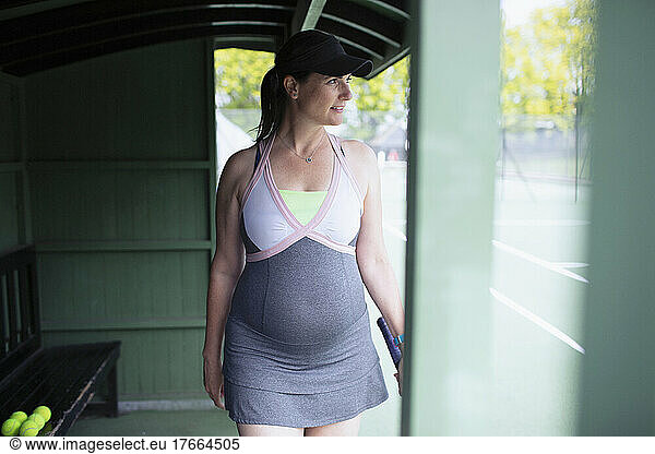 Pregnant woman in tennis dress at tennis court