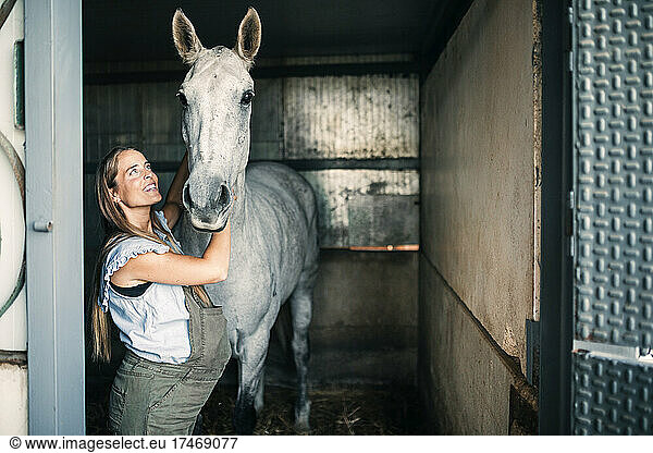 Pregnant woman looking at horse in stable