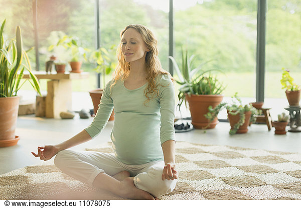 Pregnant woman meditating in lotus position