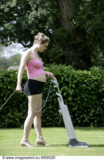 Pregnant Woman Mowing Lawn with Vaccuum Cleaner