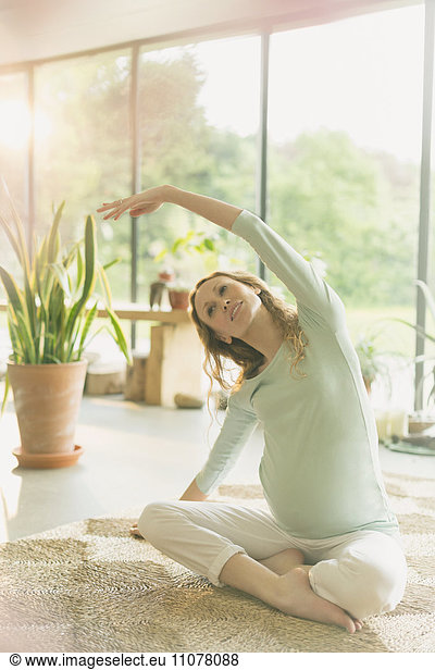 Pregnant woman practicing yoga doing side stretch