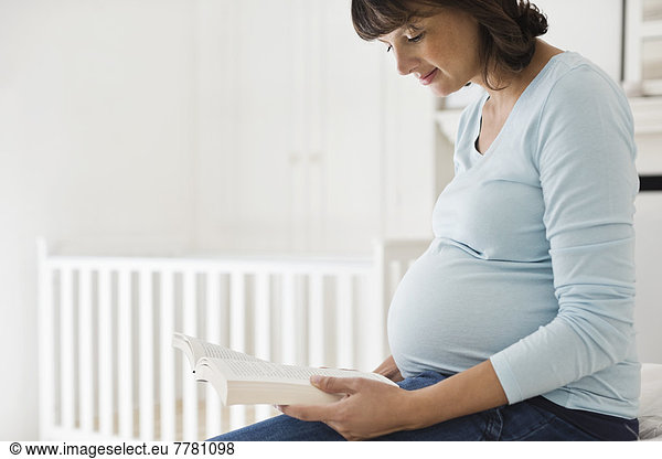 Pregnant woman reading in nursery