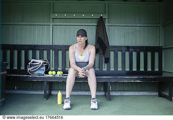 Pregnant woman resting on bench at tennis court