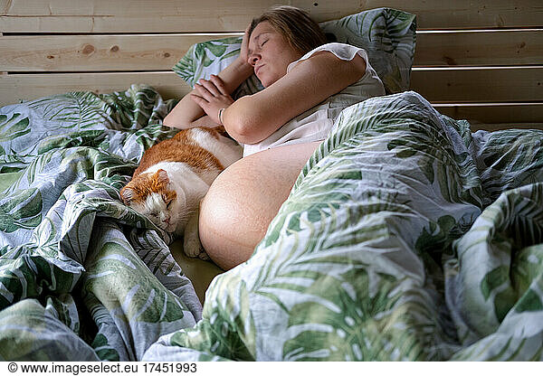 Pregnant woman sleeping in bed with her cat