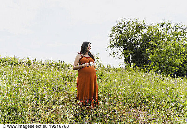 Pregnant woman standing amidst grass