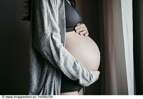 Pregnant woman touching stomach at home