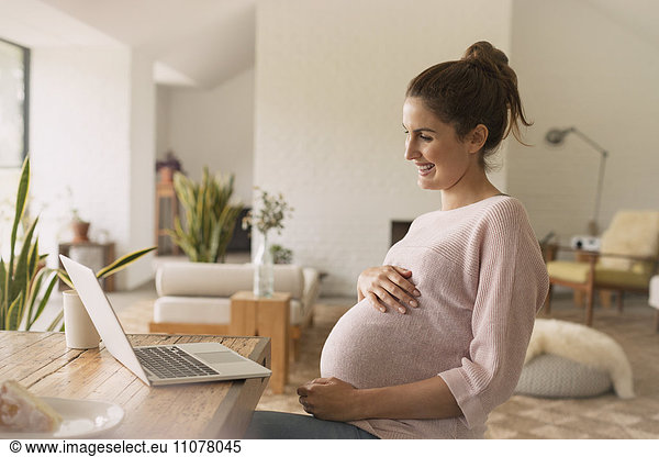 Pregnant woman video conferencing at laptop