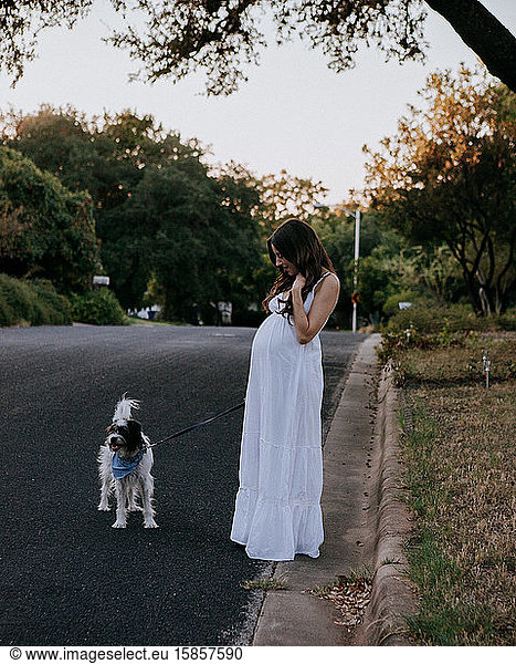 Pregnant woman white dress walking her dog