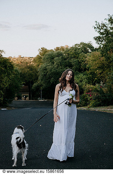 Pregnant woman white dress walking her dog