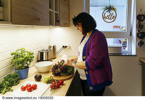 Pregnant woman with vegetables preparing food at home