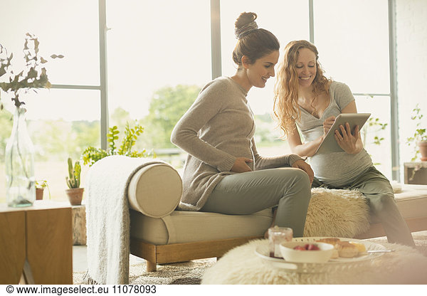 Pregnant women using digital tablet in living room