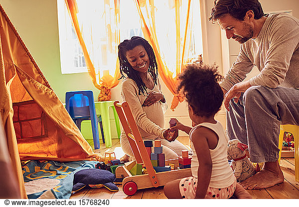 Pregnant young family playing with toys