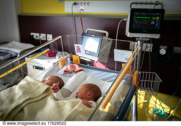 Premature twins sleeping side by side in the same bed.