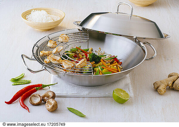 Preparation of chicken breast and vegetables in metal wok