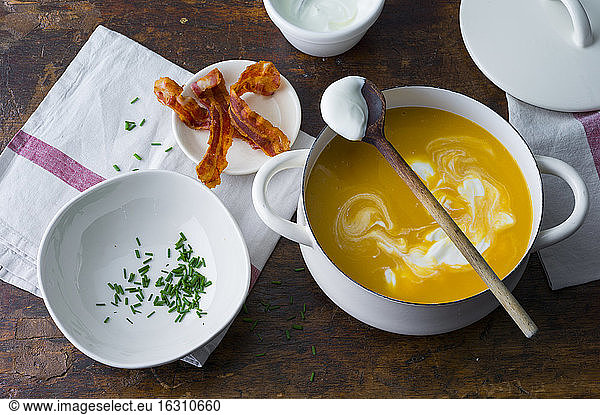 Preparation on carrot soup with bacon and creme fraiche