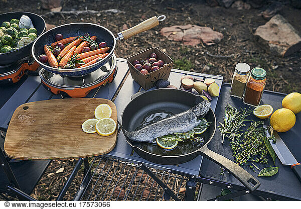 preparing camp dinner with herb stuffed trout and vegetables.
