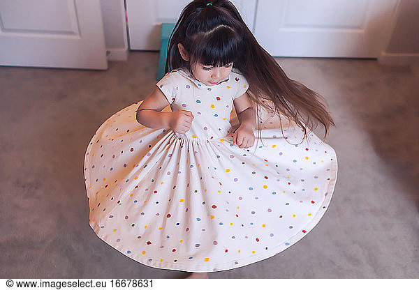 Preschool twirling in her bedroom  wearing a polka dot dress.