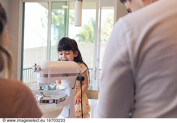 Preschooler cooking in the kitchen with her family looking amazed.