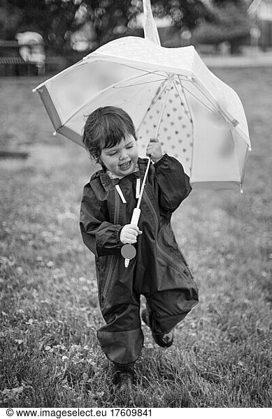 Preschooler girl walking in a park with an umbrella; North Vancouver  British Columbia  Canada
