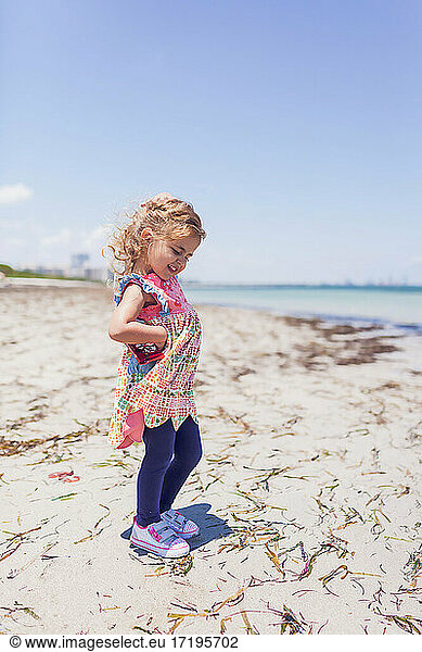 Preschooler girl walking on the beach and being sassy.