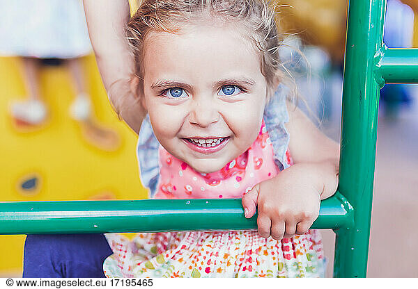Preschooler girl with big blue eyes playing at a public playground.