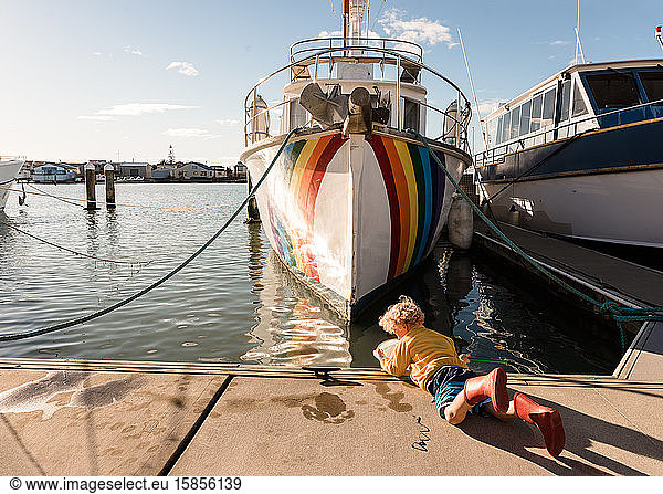 Preschooler playing with net near boat with rainbow