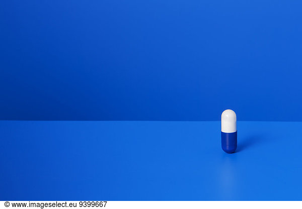 Prescription pill standing upright on blue counter