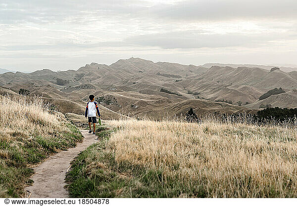 Preteen boy walking on a scenic path with mountains