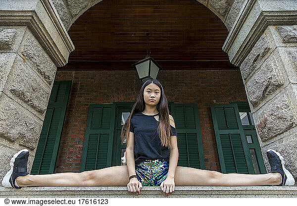 Preteen girl in a splits position on a ledge under an archway; Hong Kong  China