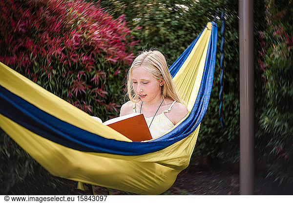 Preteen girl in hammock with a book