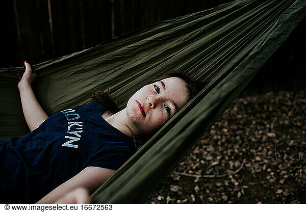 Preteen girl laying in hammock outside