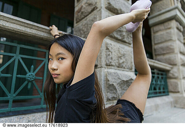 Preteen girl stretches with dance shoes; Hong Kong  China
