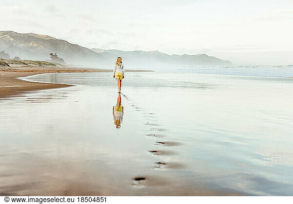 Preteen girl waling on beach in New Zealand